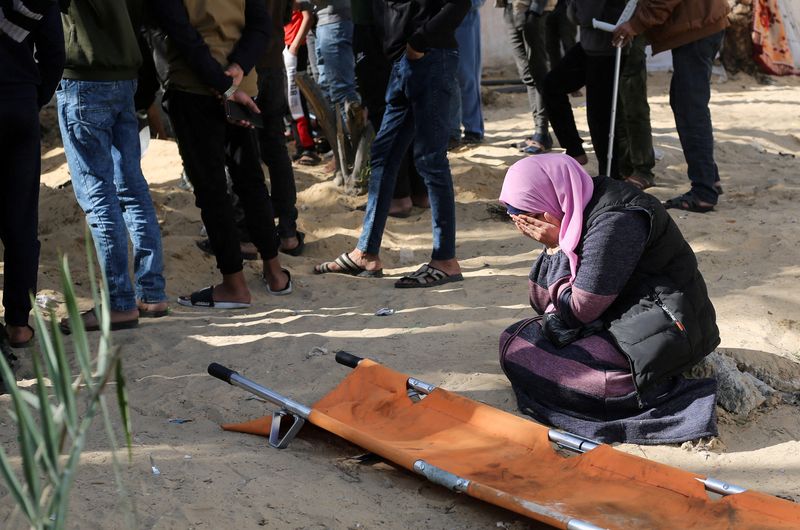 © Reuters. A woman reacts while people bury bodies of Palestinians killed in an Israeli strike, at the Nasser hospital premises as Palestinians cannot reach the cemetery due to the Israeli ground operation, in Khan Younis in the southern Gaza Strip, January 22, 2024. REUTERS/Ahmed Zakot   