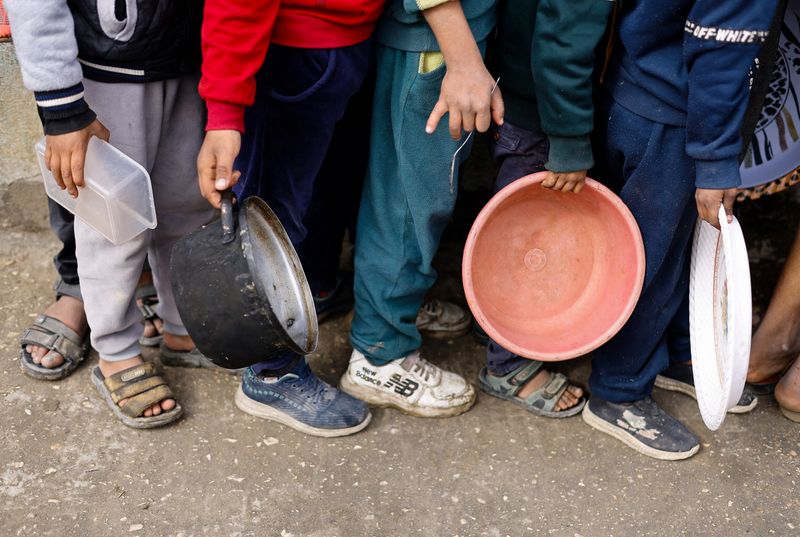 © Reuters. أطفال فلسطينيون يحملون أوعية خاوية انتظارا للحصول على طعام في ظل نقص الإمدادات الغذائية في رفح جنوب قطاع غزة يوم 17 يناير كانون الثاني 2024. تصوير: محمد سالم - رويترز.