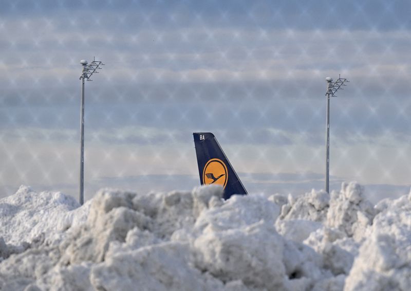 &copy; Reuters. FILE PHOTO: A tail fin of a Lufthansa plane is pictures behind snow at the terminal as Munich Airport has cancelled all incoming and outgoing flights until 12 p.m. (1100GMT) due to a forecast for sleet in Munich, Germany, December 5, 2023. Picture taken t