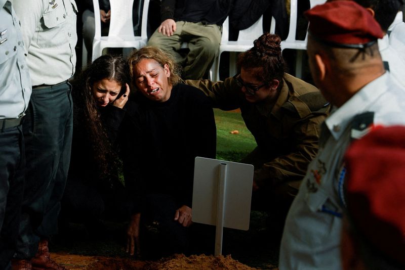 © Reuters. Mujeres reaccionan mientras amigos y familiares lloran al soldado israelí sargento mayor Ilay Levy, de 24 años, muerto en la Franja de Gaza, en su funeral en Tel Aviv, Israel,. 23 de enero de 2024. REUTERS/Tyrone Siu 