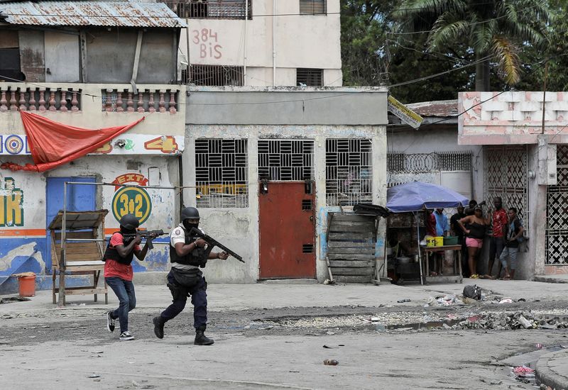 &copy; Reuters. FILE PHOTO: People huddle in a corner as police patrol the streets after gang members tried to attack a police station, in Port-au-Prince, Haiti April 25, 2023. REUTERS/Ralph Tedy Erol