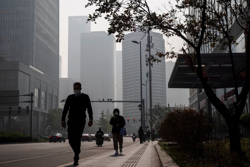 &copy; Reuters. FILE PHOTO: People walk in the Central Business District (CBD) on a hazy morning in Beijing, China, October 25, 2021.   REUTERS/Thomas Peter/File Photo