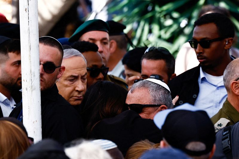 © Reuters. FILE PHOTO: Israeli cabinet minister and former military chief Gadi Eizenkot is consoled by a mourner, as Israeli Prime Minister Benjamin Netanyahu reacts, during the funeral of Gal Meir Eisenkot, 25, an Israeli solider, who was killed in northern Gaza during the ongoing ground operation by Israel's military in the Gaza Strip, in Herzliya, Israel, December 8, 2023. REUTERS/Clodagh Kilcoyne/File Photo