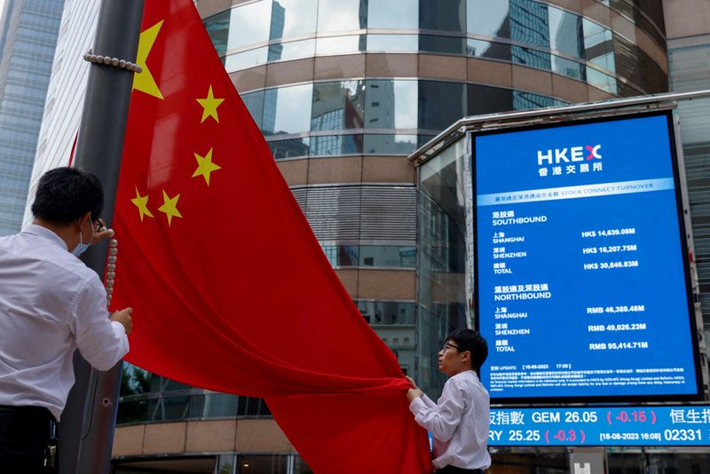&copy; Reuters. FOTO DE ARCHIVO. Personal arría la bandera nacional china frente a las pantallas que muestran el índice y los precios de las acciones fuera de Exchange Square, en Hong Kong, China. 18 de agosto de 2023. REUTERS/Tyrone Siu