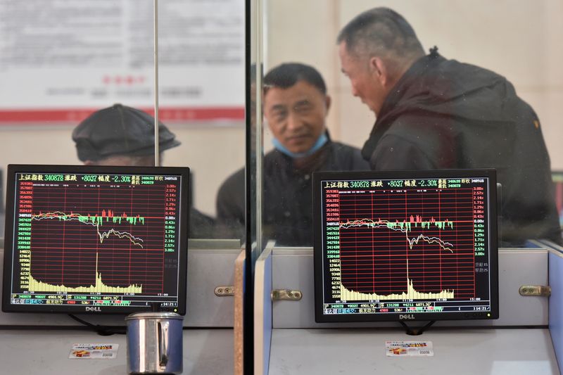 &copy; Reuters. Investors are seen behind screens displaying stock information at a brokerage house in Fuyang, Anhui province, China February 24, 2022. China Daily via REUTERS