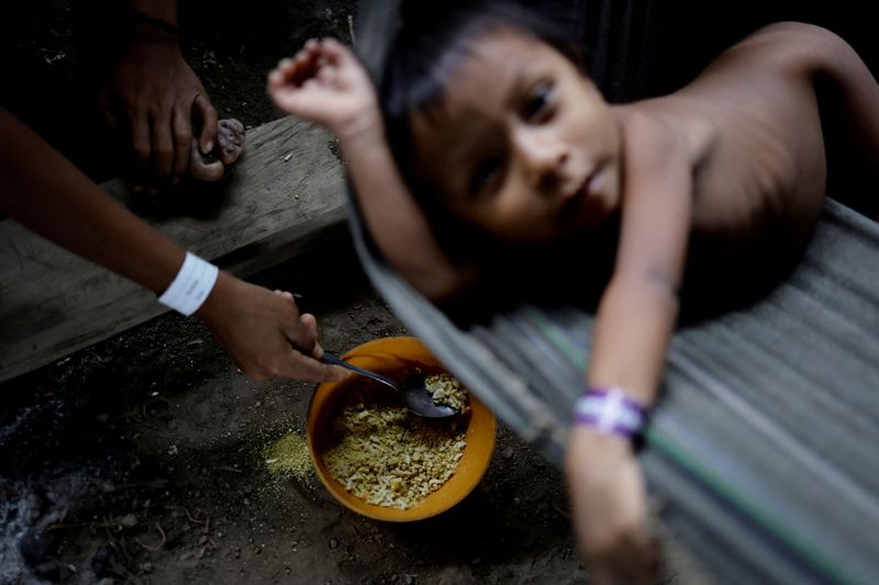 &copy; Reuters. A Yanomami child is fed a mix of rice and farofa by his mother while receiving healthcare in the accommodation used to shelter the sick, at the healthcare unit of the Auaris Base Hub, in Yanomami Indigenous land, Roraima state, Brazil, January 10, 2024. R