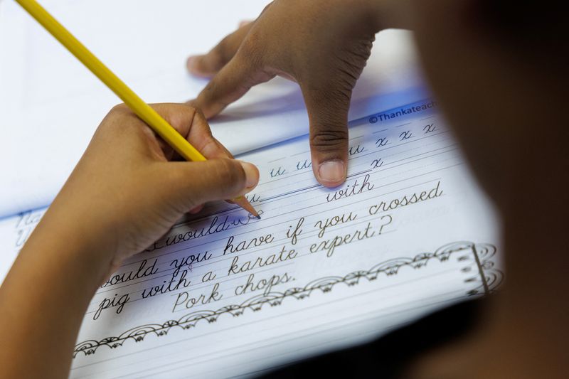 © Reuters. A student at Orangethorpe Elementary School practices writing cursive as California grade school students are being required to learn cursive handwriting this year, in Fullerton, California, U.S. January 23, 2024. REUTERS/Mike Blake