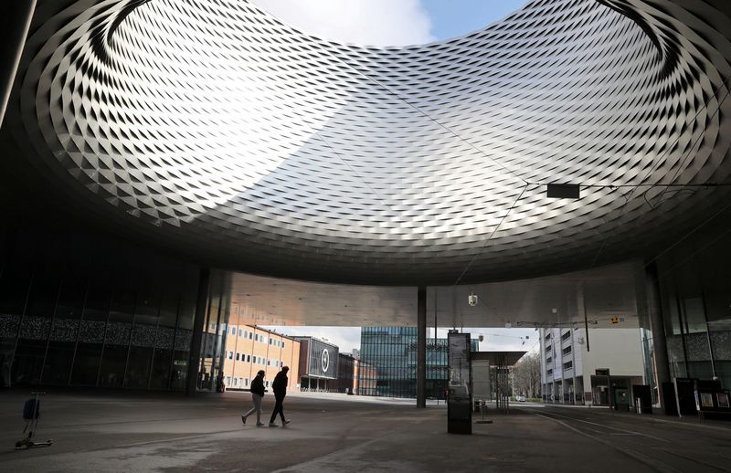 &copy; Reuters. People walk under the open roof of between the halls of the Messe Basel fairground designed by Swiss architects Herzog & de Meuron at the Messeplatz square in Basel, Switzerland March 18, 2021. REUTERS/Arnd Wiegmann/File Photo