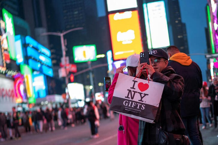 © Reuters. A man takes a picture while carrying a shopping bag in Times Square, New York, U.S., December 25, 2023. REUTERS/Eduardo Munoz/files