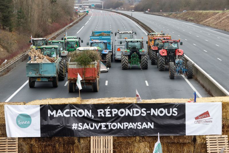 &copy; Reuters. インフレや安価な輸入品、生活支援への対応を求めて政府に圧力をかける農家の抗議活動が欧州全土に広がっている。写真はパリ近郊で３０日、道路を封鎖する農家のトラクター。「マクロ