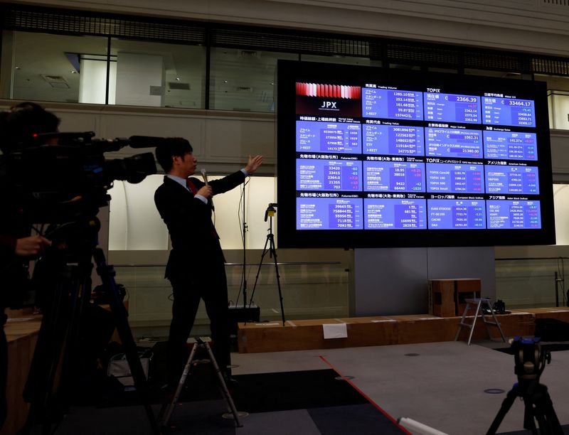 &copy; Reuters. مراسل تلفزيوني يشير إلى لوحة إلكترونية تعرض ببيانات مؤشر نيكي الياباني في بورصة طوكيو يوم 29 ديسمبر كانون الأول 2023. تصوير: كيم كيونج هوون - رو