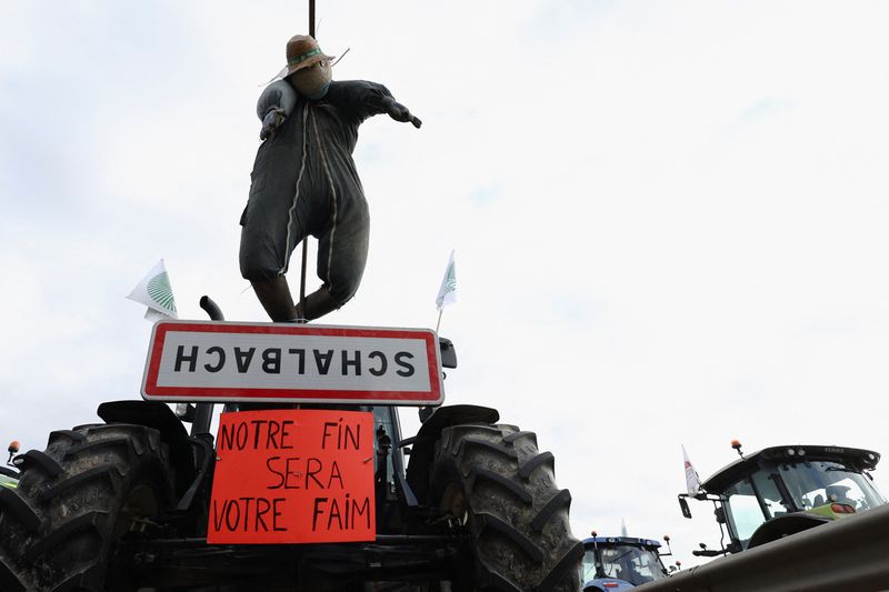 &copy; Reuters. An effigy and a placard reading "Our end will be your hunger" are attached to a tractor as farm vehicles are lined up during a blockade by farmers on the A4 highway to protest over price pressures, taxes and green regulation, grievances that are shared by