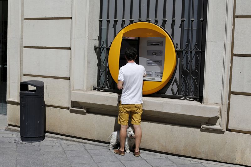&copy; Reuters. Un umo preleva del denaro a Siviglia. 28 agosto 2015. REUTERS/Marcelo del Pozo
