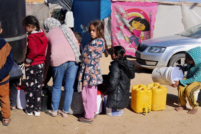 &copy; Reuters. Niños palestinos desplazados, que huyeron de sus casas debido a los ataques israelíes, esperan para recoger agua en medio de la escasez, en un campamento de tiendas de campaña en Rafah, en el sur de la Franja de Gaza. 1 de febrero de 2024. REUTERS/Sale