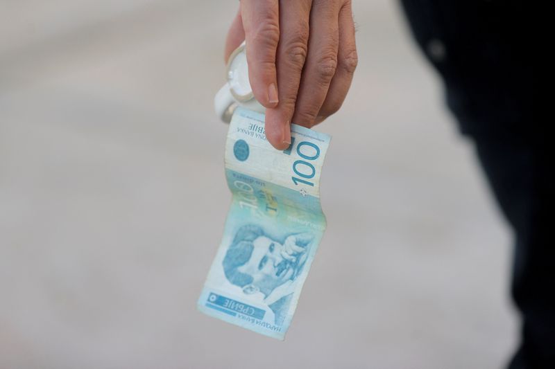 &copy; Reuters. A man holds a dinar currency and a coffee cup in Mitrovica, Kosovo, February 1, 2024. The Kosovo government will ban the Serbian dinar in minority regions despite warnings from the EU and the U.S. that such could fuel ethnic tensions in the volatile north