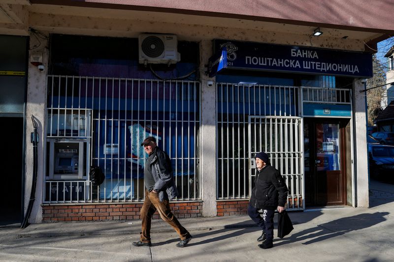 © Reuters. Pedestrians walk past a bank in Mitrovica, Kosovo, February 1, 2024. The Kosovo government will ban the Serbian dinar in minority regions despite warnings from the EU and the U.S. that such could fuel ethnic tensions in the volatile north. REUTERS/Valdrin Xhemaj