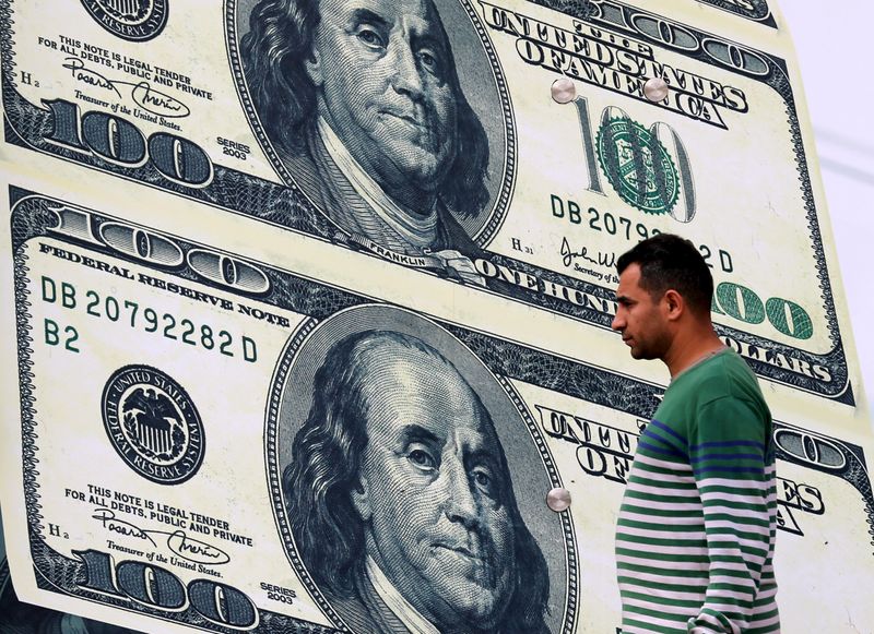 &copy; Reuters. رجل يسير أمام مكتب صرافة يعرض صورا للدولار الأمريكي في القاهرة بصورة من أرشيف رويترز.
