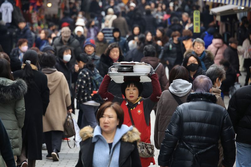 &copy; Reuters. A woman carrying meals on her head makes her way through shoppers at a traditional market in Seoul, South Korea, January 4, 2024.   REUTERS/Kim Hong-Ji/File Photo