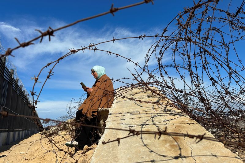 © Reuters. A displaced Palestinian woman tries to get internet signal to communicate with her relatives, amid the ongoing conflict between Israel and Hamas, at the border with Egypt, in Rafah in the southern Gaza Strip February 1, 2024. REUTERS/Mohammed Salem
