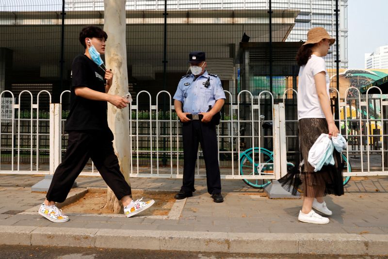 © Reuters. People walk past a police officer keeping watch outside the U.S. embassy in Beijing, China August 4, 2022. REUTERS/Carlos Garcia Rawlins