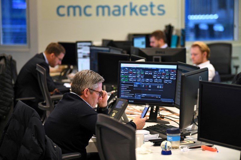 &copy; Reuters. FILE PHOTO: Dealers work at their desks whilst screens show market data at CMC Markets in London, Britain, January 30, 2019. REUTERS/Dylan Martinez/File Photo