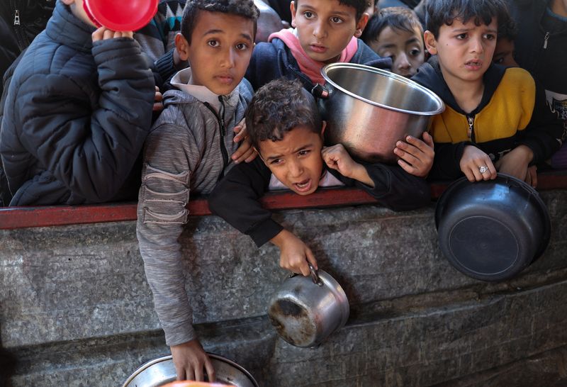 &copy; Reuters. Niños palestinos esperando para recibir alimentos cocinados por una cocina de caridad en medio de la escasez de suministros de alimentos, en Ráfah, en el sur de la Franja de Gaza, mientras continúa el conflicto en curso entre Israel y el grupo islamist
