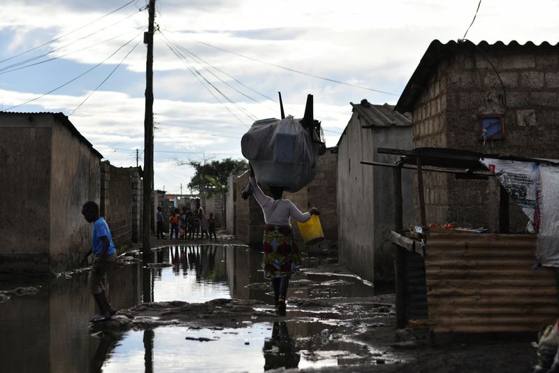 &copy; Reuters. People walk across a flooded street in a neighbourhood affected by the cholera outbreak in Lusaka, Zambia January 18, 2024. REUTERS/Namukolo Siyumbwa/File Photo