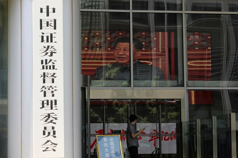 &copy; Reuters. FILE PHOTO: A man stands near a screen showing news footage of Chinese President Xi Jinping at the China Securities Regulatory Commission (CSRC) building on the Financial Street in Beijing, China July 9, 2021. REUTERS/Tingshu Wang/File Photo