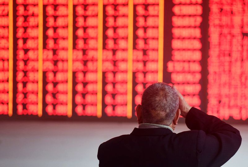 &copy; Reuters. FILE PHOTO: A man sits in front of an electronic board showing stock information at a brokerage house in Hangzhou, Zhejiang province, China December 3, 2018. REUTERS/Stringer  