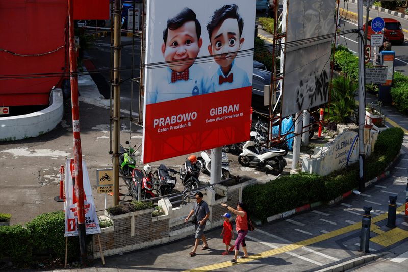 &copy; Reuters. FILE PHOTO: People walk past a billboard promoting Indonesia's Defence Minister and Presidential candidate Prabowo Subianto and his running mate Gibran Rakabuming Raka, who is the eldest son of Indonesian President Joko Widodo and current Surakarta's May