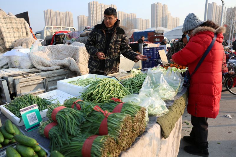 © Reuters. بائع خضراوات يأخذ المال من زبونة في بكين يوم 12 يناير كانون الثاني 2024. تصوير: فلورنس لو - رويترز.