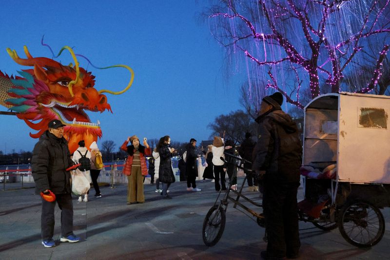 &copy; Reuters. A tricycle driver waits for customers as visitors take pictures with a dragon installation ahead of the Lunar New Year in Beijing, China February 7, 2024. REUTERS/Florence Lo