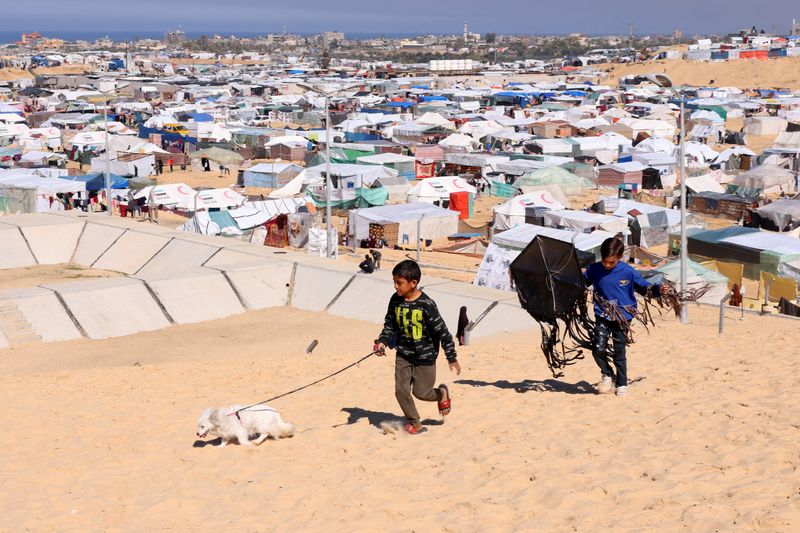 &copy; Reuters. Children walk with a dog, as displaced Palestinians, who fled their houses due to Israeli strikes, take shelter in a tent camp, amid the ongoing conflict between Israel and the Palestinian Islamist group Hamas, at the border with Egypt, in Rafah in the so