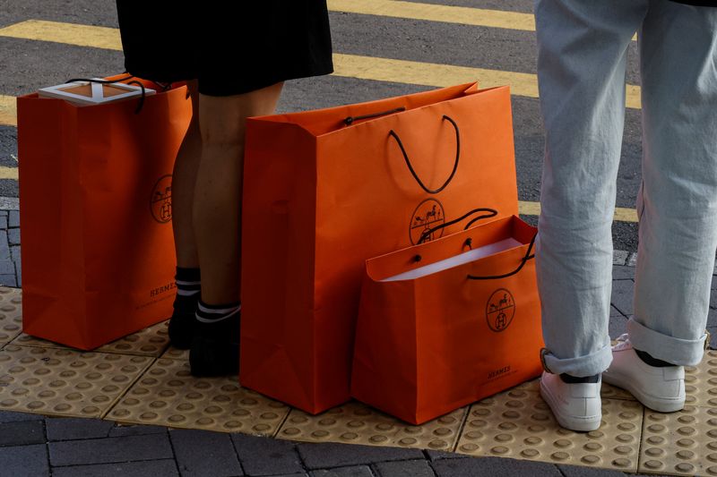 © Reuters. FILE PHOTO: People stand with Hermes shopping bags as they wait at a traffic light in Tsim Sha Tsui, a bustling shopping hotspot, in Hong Kong, China December 5, 2023. REUTERS/Tyrone Siu/File Photo