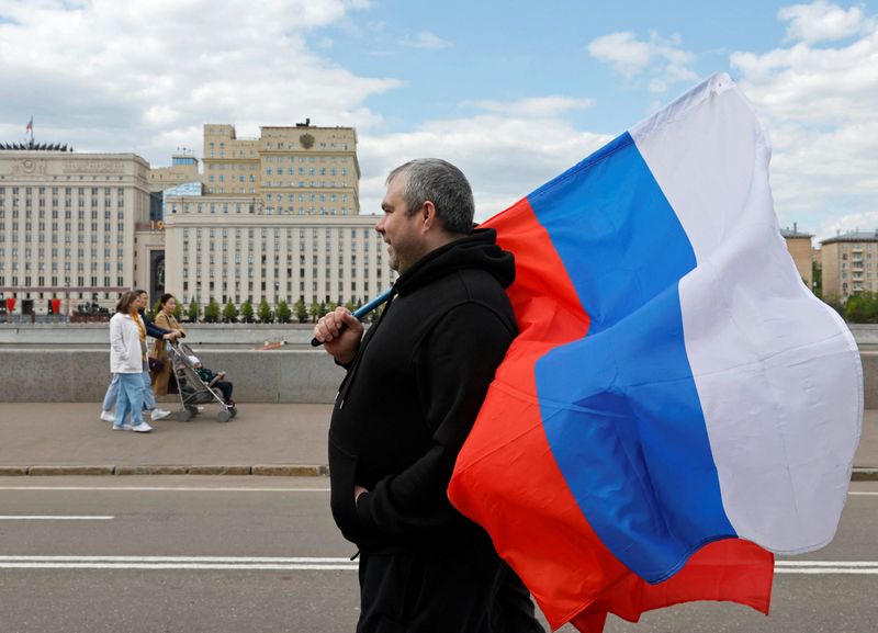 &copy; Reuters. رجل يحمل العلم الروسي بينما تسير سيدات بالقرب من مبنى وزارة الدفاع الروسية بموسكو في التاسع من مايو أيار 2023 . تصوير: شامل زوماتوف - رويترز