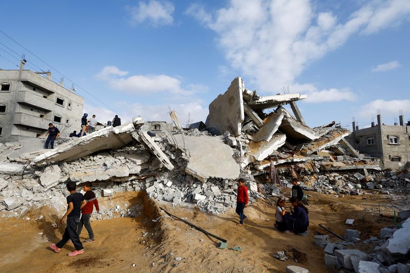 &copy; Reuters. Unos niños pasan junto a unos palestinos que inspeccionan el lugar donde se ha producido un ataque israelí contra una casa, en Rafah, en el sur de la Franja de Gaza
April 21, 2024. REUTERS/Mohammed Salem/
