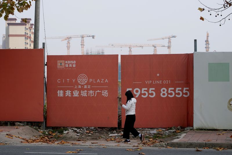&copy; Reuters. FILE PHOTO: A woman walks past a construction site of Kaisa Group Holdings, in Shanghai, China, December 7, 2021. REUTERS/Aly Song/File Photo