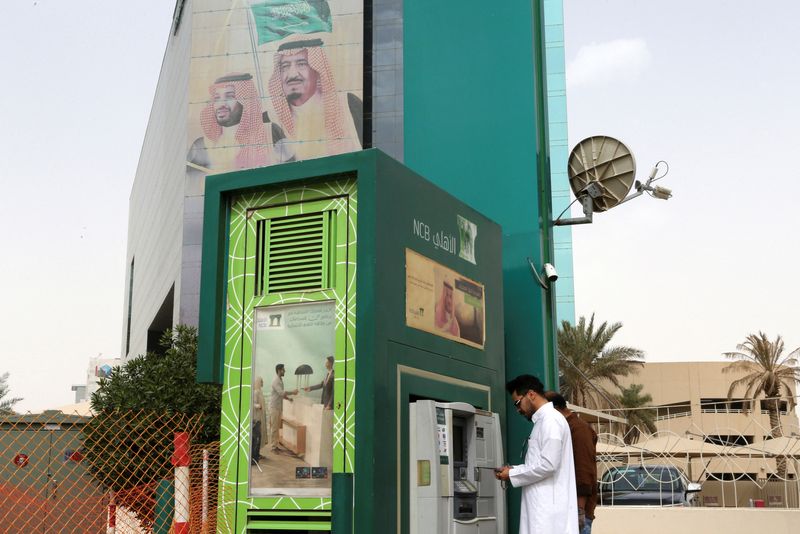 &copy; Reuters. رجل يسحب أموالاً من ماكينة صراف آلي خارج البنك الوطني التجاري السعودي في صورة من أرشيف رويترز.