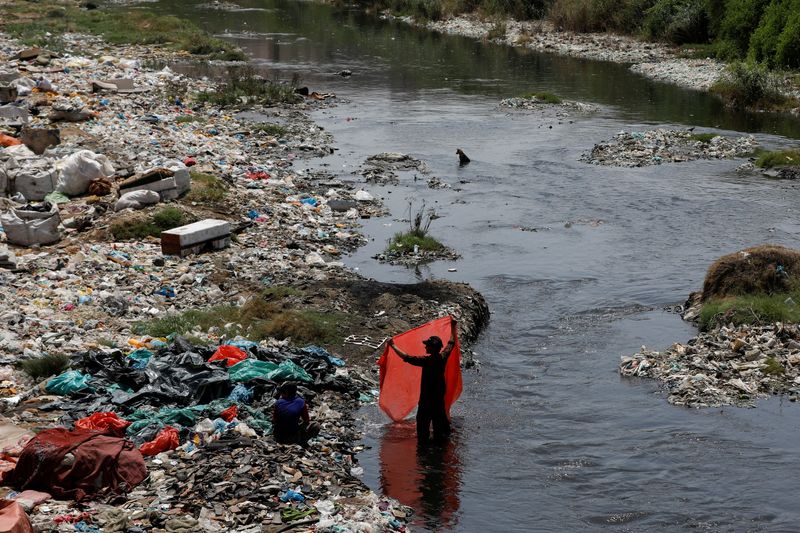 © Reuters. FOTO DE ARCHIVO: Un hombre lava láminas de plástico de desecho, recogidas para su reciclaje, en aguas contaminadas en Karachi, Pakistán 5 de junio de 2023. REUTERS/Akhtar Soomro/Foto de archivo