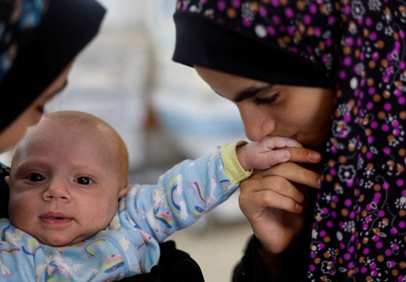 &copy; Reuters. فتاة تقبل يد يحيى حمودة، رضيع فلسطيني، جرى نقله إلى جنوب غزة عندما كان طفلا مبتسرا بعدما داهمت القوات الإسرائيلية مستشفى كمال عدوان في شمال 