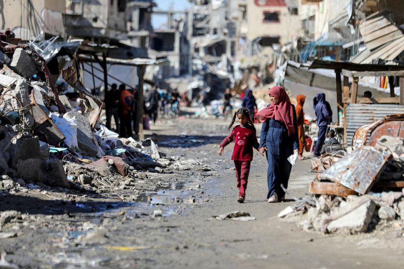 &copy; Reuters. FILE PHOTO: Palestinians walk past the ruins of houses destroyed during Israel's military offensive, amid the ongoing conflict between Israel and Hamas, in Gaza City, March 20, 2024. REUTERS/Dawoud Abu Alkas//File Photo
