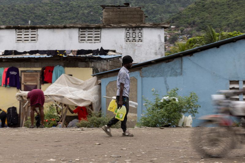 © Reuters. Un hombre lleva contenedores llenos de gasolina para vender en las calles de Cap-Haitien, Haití 29 de abril 2024. REUTERS/Ricardo Arduengo
