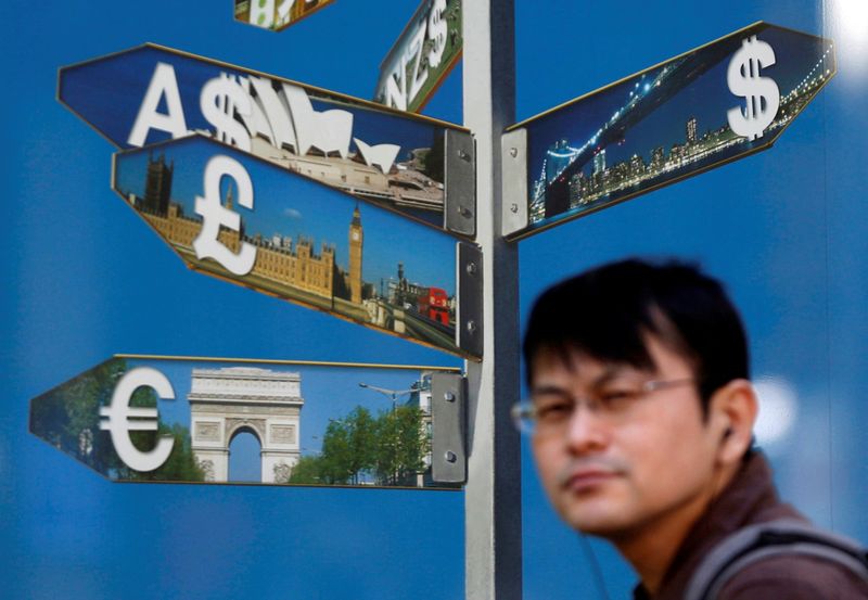 © Reuters. A man walks past various currency signs outside a brokerage in Tokyo October 28, 2014. REUTERS/Yuya Shino/File Photo