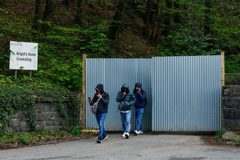 © Reuters. Asylum seekers walk past the gate of an International Protection Accommodation Service (IPAS) tented accommodation service, provided to asylum seekers that were moved from Dublin City, in Crooksling, Ireland, May 1, 2024.  REUTERS/Clodagh Kilcoyne