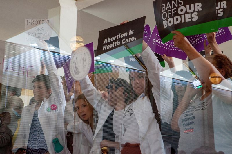 © Reuters. FILE PHOTO: North Carolina physicians hold signs to protest as North Carolina Republican lawmakers hold a vote to override Democratic Governor Roy Cooper's veto of a bill that would ban most abortions in the state after 12 weeks, in Raleigh, North Carolina, U.S. May 16, 2023. REUTERS/Erin Siegal McIntyre/File Photo