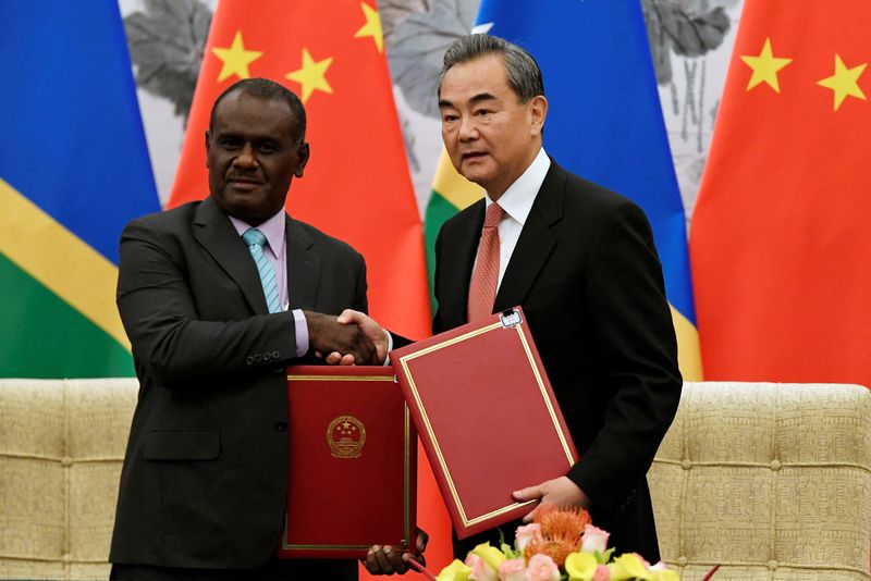 © Reuters. FILE PHOTO: Chinese State Councilor and Foreign Minister Wang Yi shakes hands with Solomon Islands Foreign Minister Jeremiah Manele during a ceremony to mark the establishment of diplomatic ties between the two nations at the Diaoyutai State Guesthouse in Beijing, China, September 21, 2019. Naohiko Hatta/Pool via REUTERS/File Photo