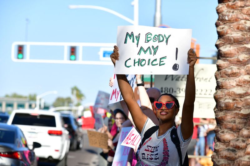 © Reuters. FILE PHOTO: A woman holds a sign at a protest in the district of Republican state Representative Matt Gress after Arizona's Supreme Court revived a law dating to 1864 that bans abortion in virtually all instances, in Scottsdale, Arizona, U.S. April 14, 2024.  REUTERS/Caitlin O’Hara/File Photo