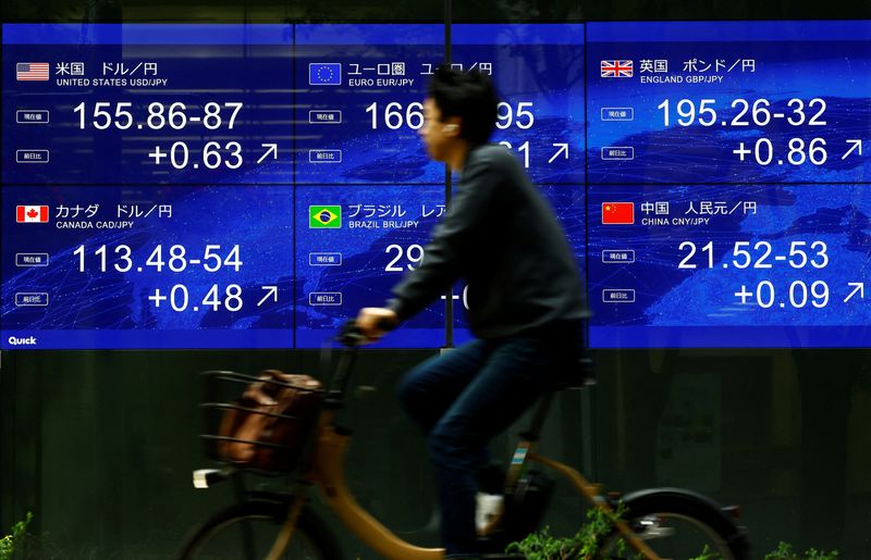 &copy; Reuters. Un uomo va in bicicletta davanti a uno schermo elettronico che mostra l'attuale tasso di cambio dello yen rispetto al dollaro e ad altre valute estere a Tokyo, Giappone, 2 maggio 2024, REUTERS/Issei Kato