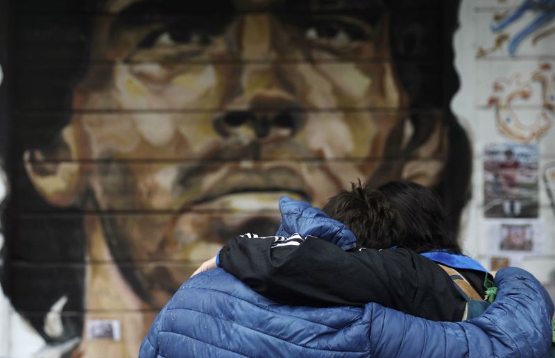 &copy; Reuters. Foto de archivo: dos personas se abrazan tras la muerte de Diego Maraadona en Buenos Aires. 28 nov, 2020. REUTERS/Ricardo Moraes