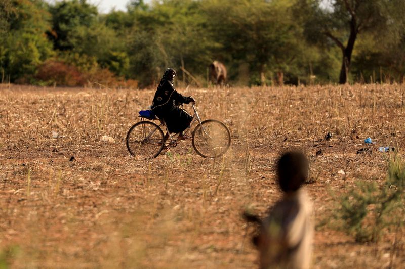 &copy; Reuters. FILE PHOTO: A child who fled with his parents from attacks of armed militants in the Sahel region watches a woman on a bicycle at a camp for internally displaced people (IDPs) in Kaya, Burkina Faso November 23, 2020. REUTERS/Zohra Bensemra/File Photo